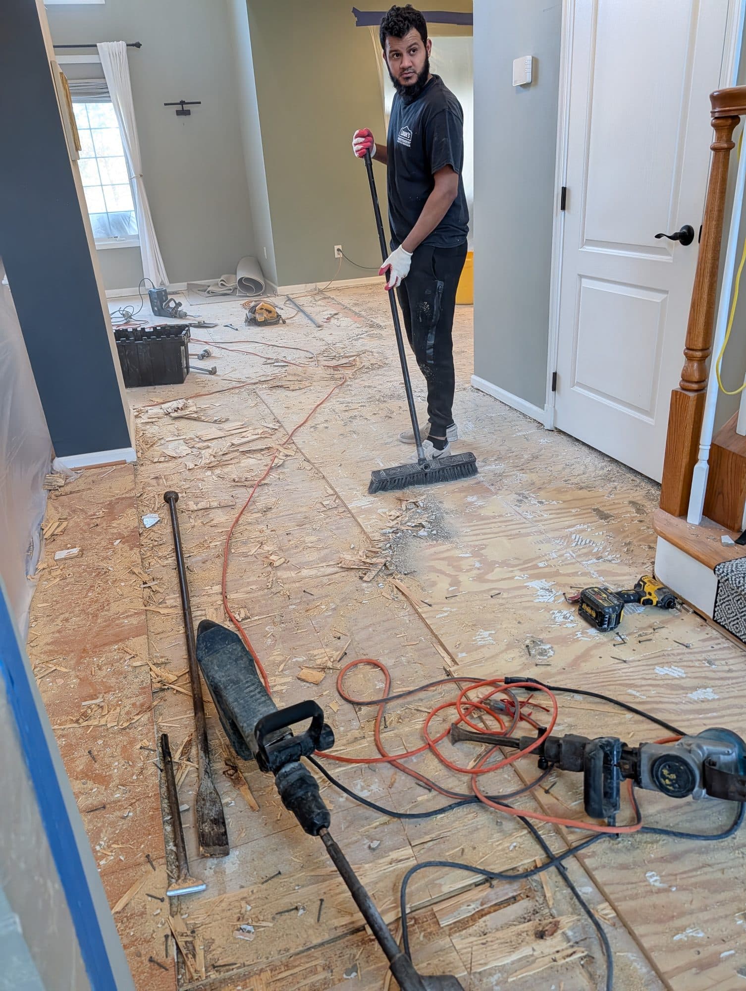 Flooring crew clearing subfloor debris during a flooring tear-out