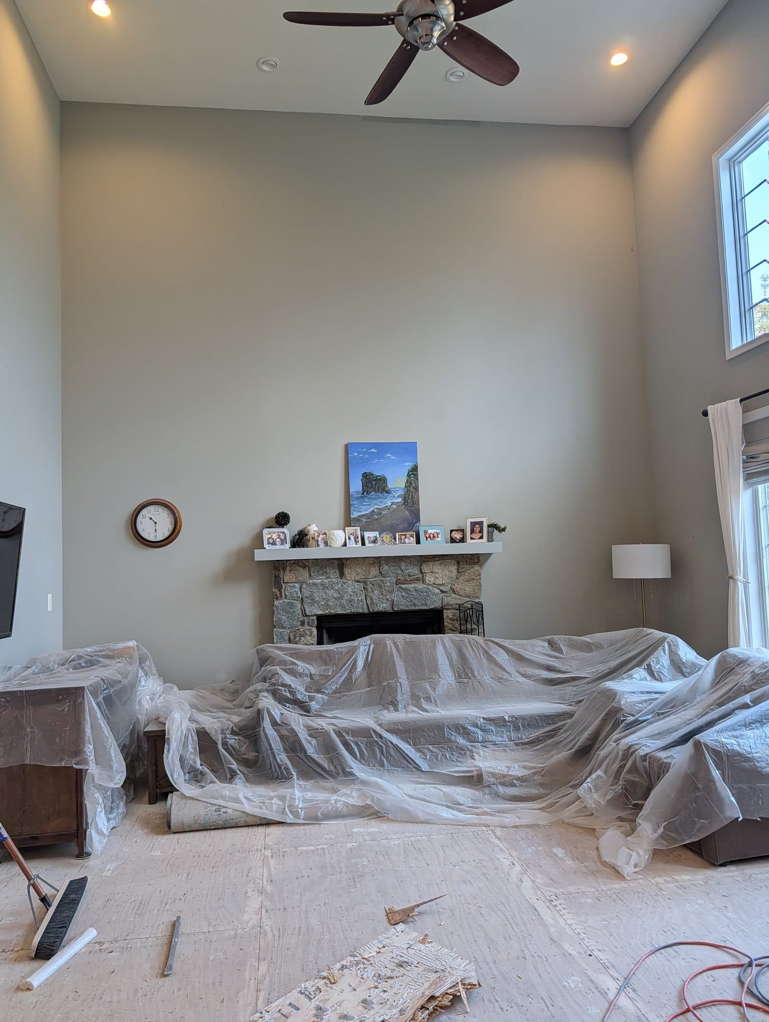Room prepped for flooring work with furniture covered and subfloor exposed