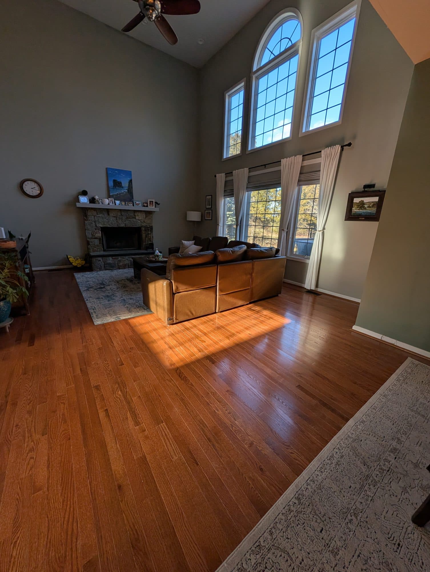 Refinished hardwood floor in a living room with a stone fireplace
