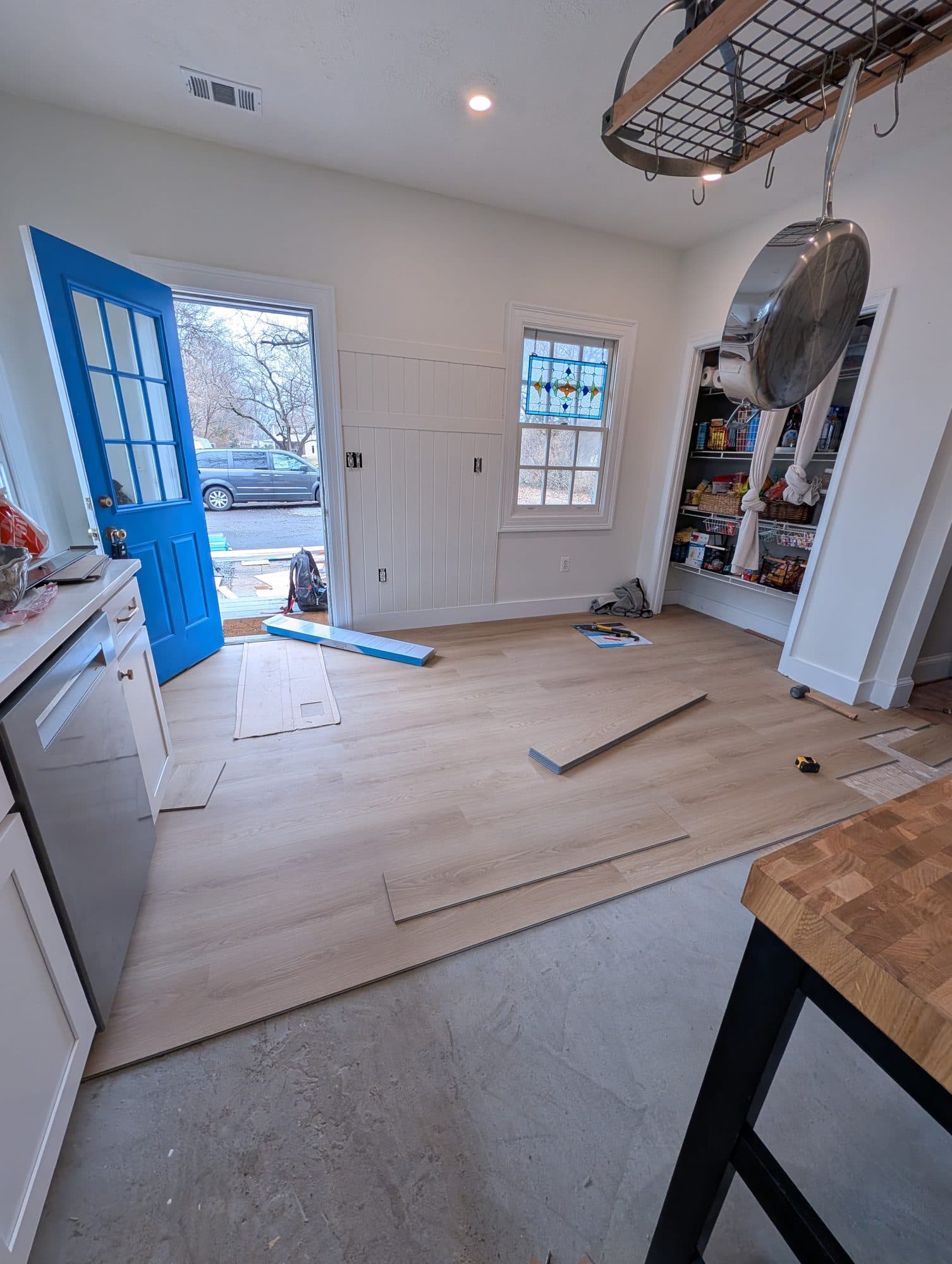 New vinyl plank flooring partway installed in a mudroom and pantry area