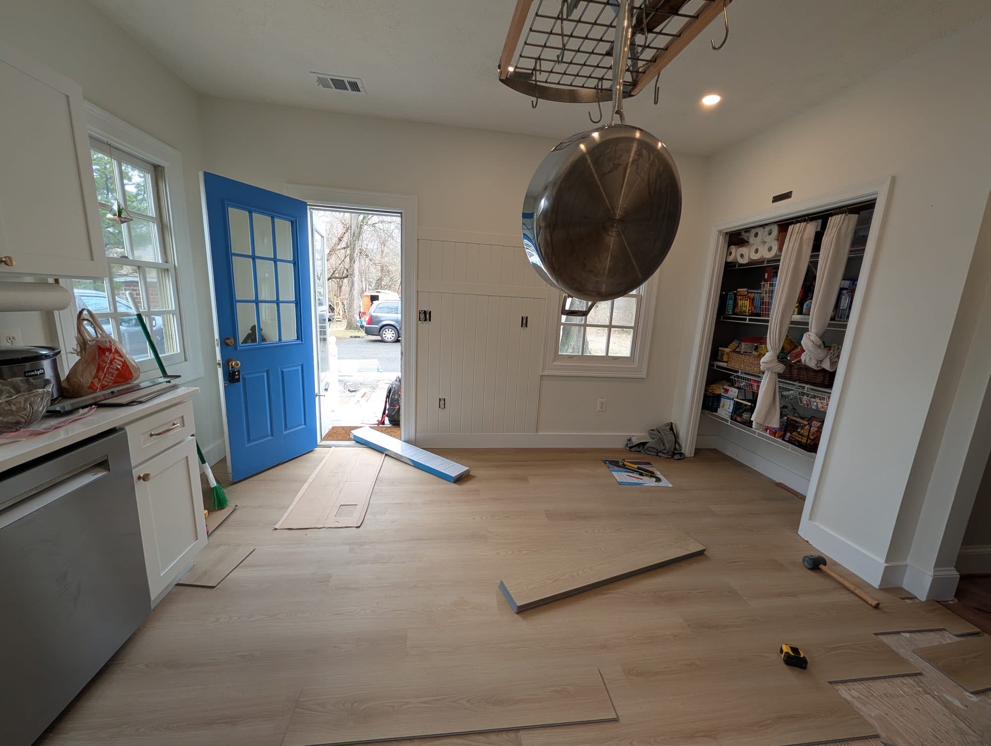 New vinyl plank flooring installed through a mudroom with a pantry and pot rack