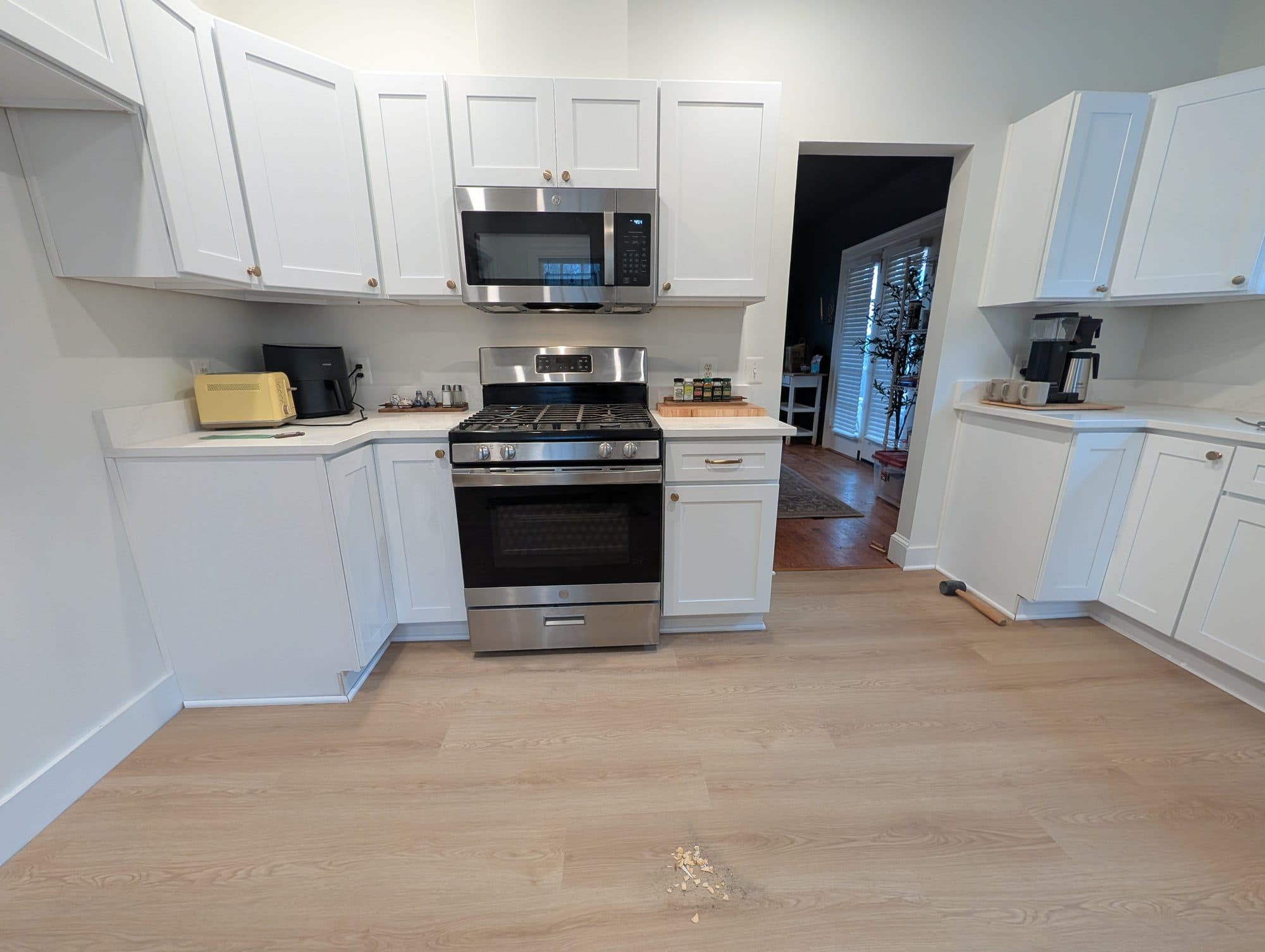 Finished vinyl plank flooring in a kitchen with white cabinetry